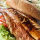 Blackened grouper filet on a sandwich bun with lettuce and tomato.